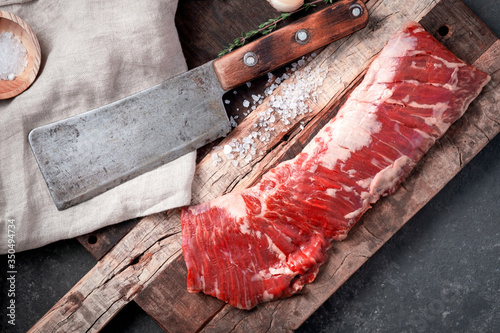 Raw beef machete steak with meat axe on a wooden Board with seasoning. Stone background.
