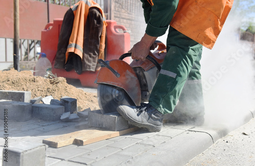 A worker on a construction site saws a curb.