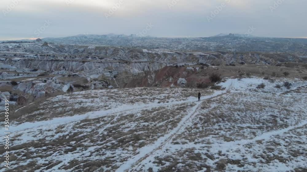 Aerial landscape of woman alone at snow covered Red Valley with its spectacular volcanic rock formations in Cappadocia, Turkey. Aerial landscape of woman alone at snow covered Red Valley with its spectacular volcanic rock formations in Cappadocia, Turkey.
