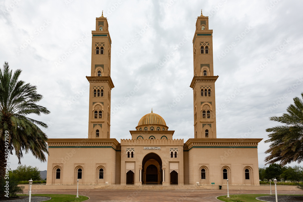 Sultan Qaboos Mosque in Bahla, Oman with two minarets against clouded sky