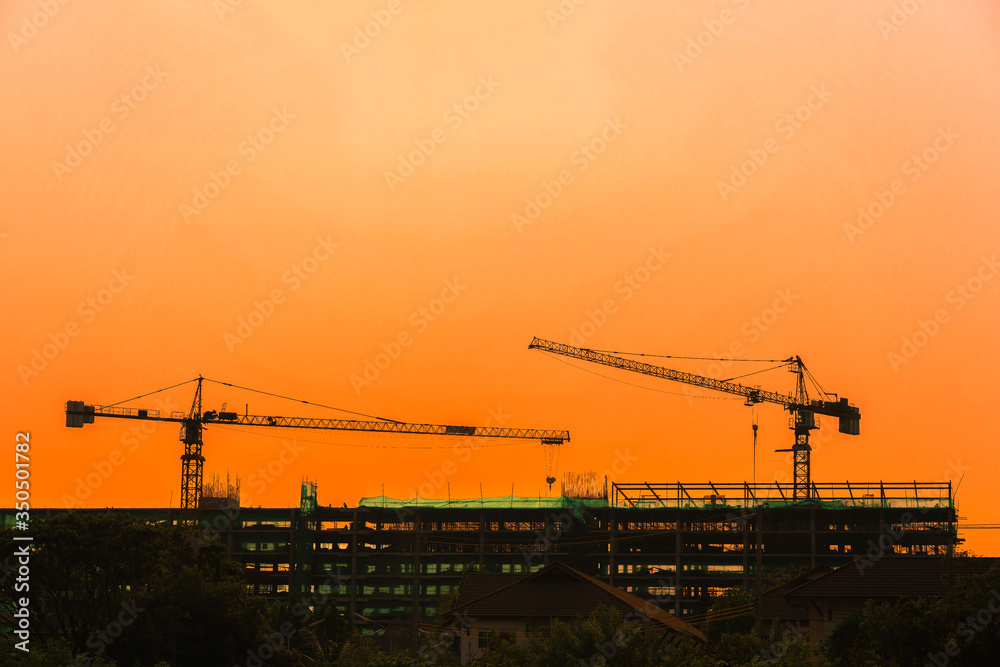 Silhouette tower crane and building on site Industrial construction on sunset background