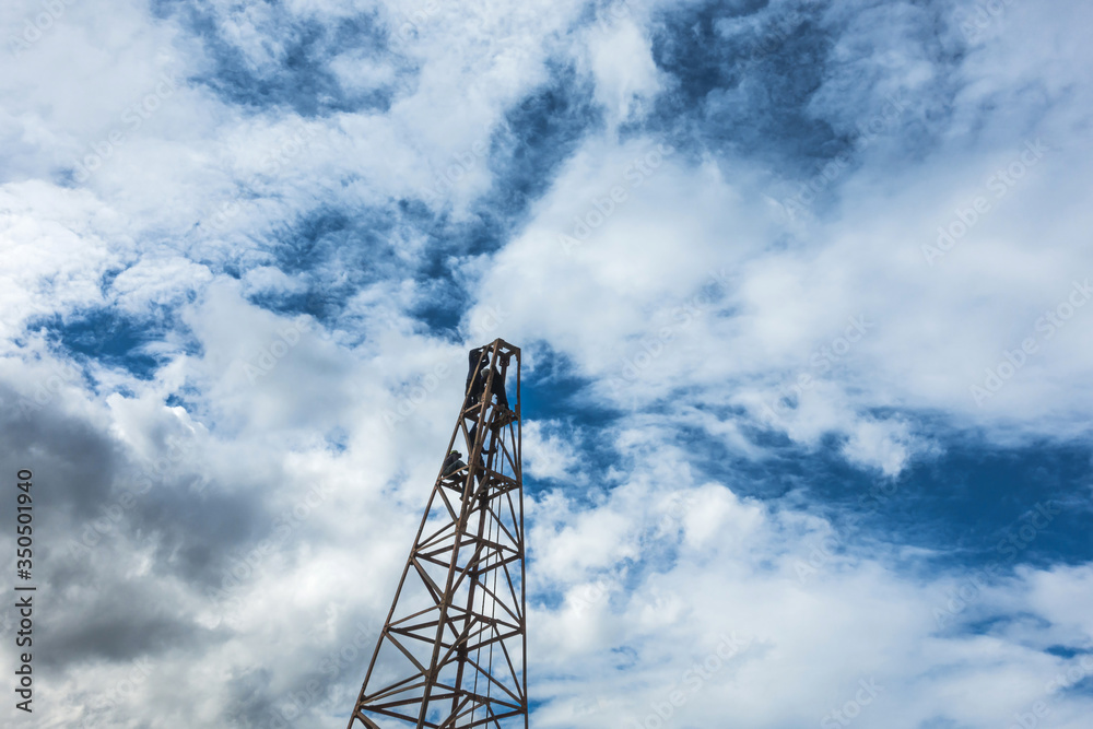 Construction worker working on scaffolding with ladder on building site and beautiful cloud, sky background Construction worker working on scaffolding with ladder on building site and beautiful cloud, sky background