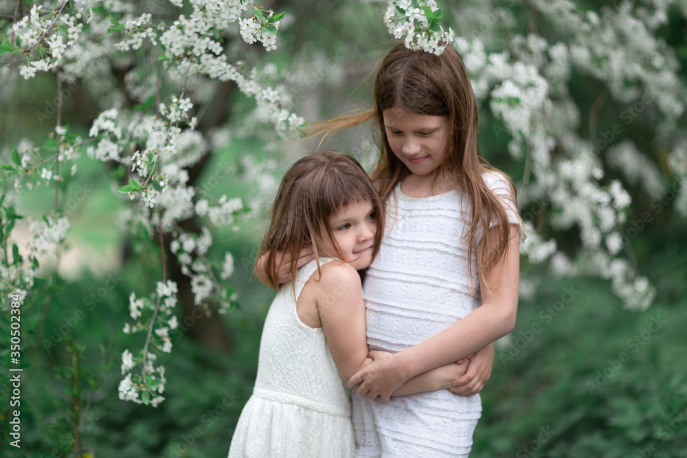 Tender children hugging near flowering tree Tender children hugging near flowering tree