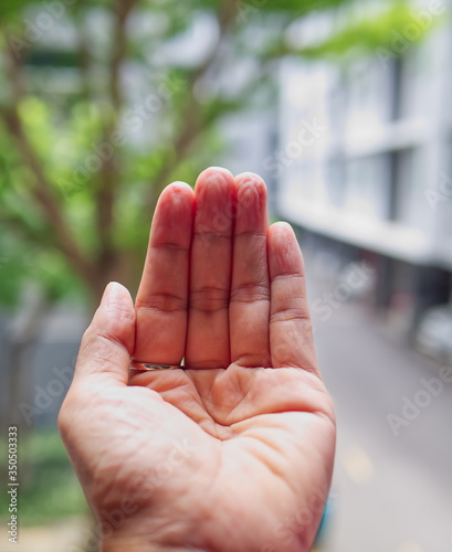 wrinkled hand/fingers because of soak in the water for a long time, blurred background.