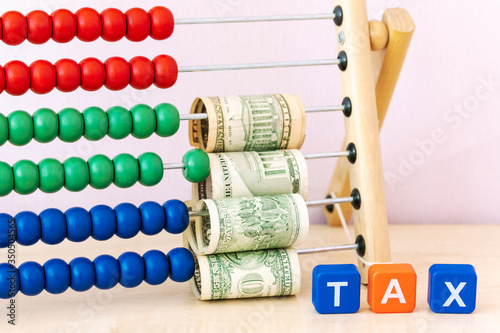 Tax Concept with tax word from plastic blocks and  dollars currency money on childs bright scores.