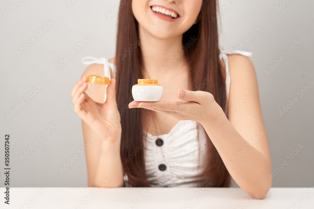 Beautiful woman showing cosmetic cream treatment over white background Beautiful woman showing cosmetic cream treatment over white background