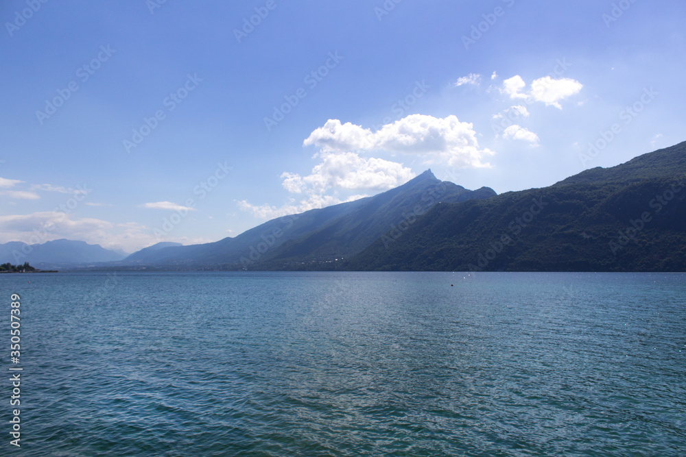 Beautiful panoramic lake shore with alps mountain range view summer water sports hiking camping concept Beautiful panoramic lake shore with alps mountain range view summer water sports hiking camping concept