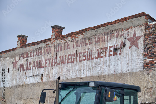 old communist inscription on a demolished house's firewall in romanian and hungarian. Traslation: workers of the world, unite! photo