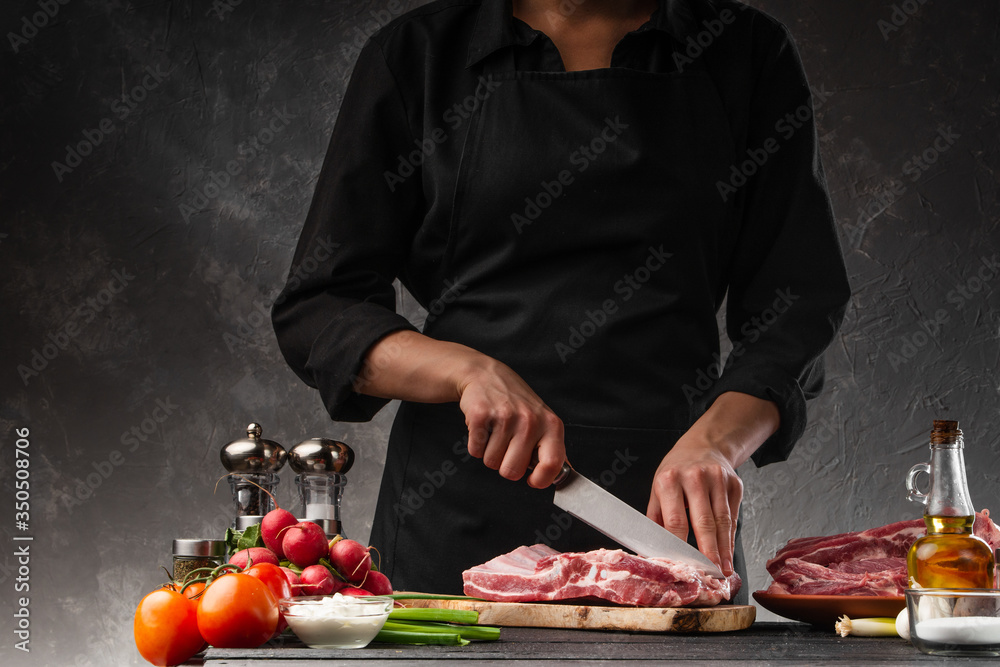 Slicing fresh pork ribs for frying on a background of vegetables. Cooking