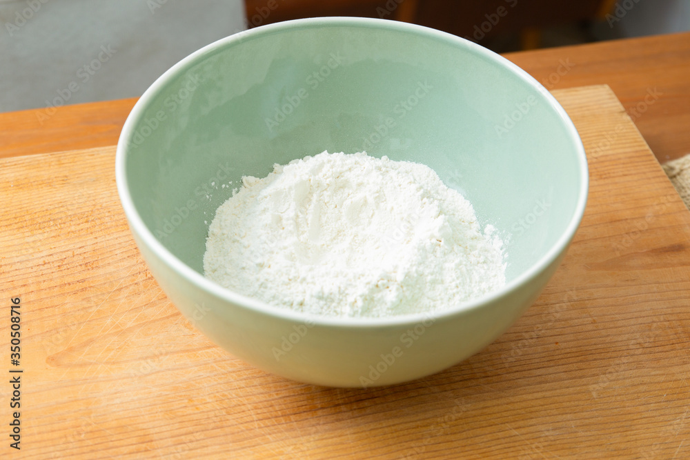 White wheat flour in ceramic bowl. Dough preparation for delicious pastry and bread. Studio shot. Side view. Homemade food and nutrition concept