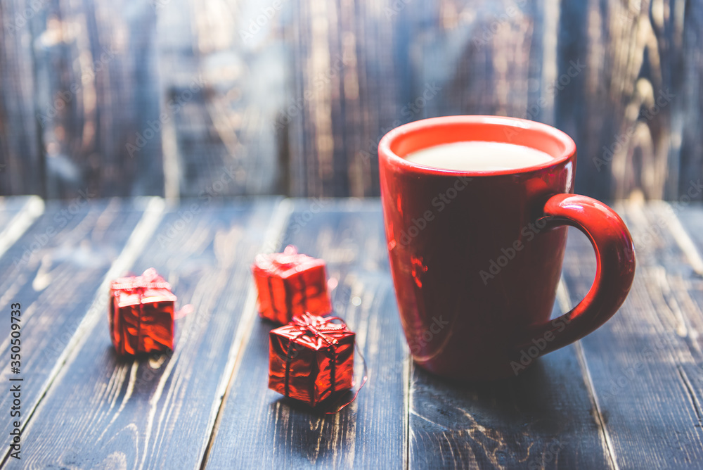 Φωτογραφία a red cup of coffee with red Christmas ornament on the dark wooden background