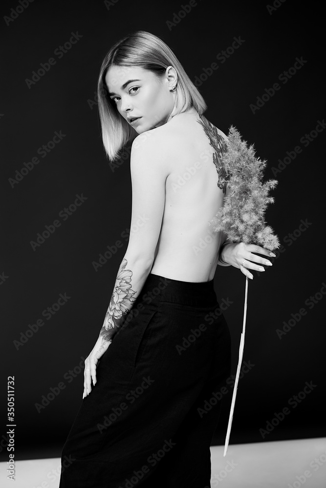 Obraz premium Portrait of a pretty blonde woman standing looking to the camera holding a wheat stalk 