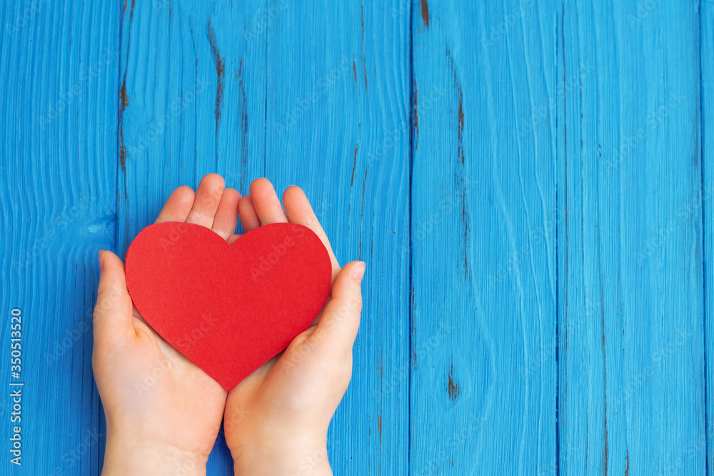Red heart on the child's hands on wooden background. Healthcare medical concept. Copy space. Top view. Red heart on the child's hands on wooden background. Healthcare medical concept. Copy space. Top view.