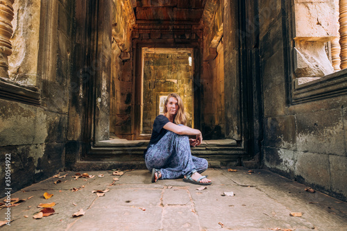 Cambodia. corridors of angkor wat. A girl with beautiful long blond hair is sitting on the floor. Ruins, Antiquity. Ancient architecture. Travels