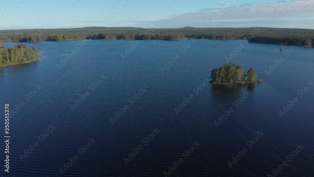 Aerial view of a Swedish lake with a small island inside a forest during a warm summer day. Aerial view of a Swedish lake with a small island inside a forest during a warm summer day.