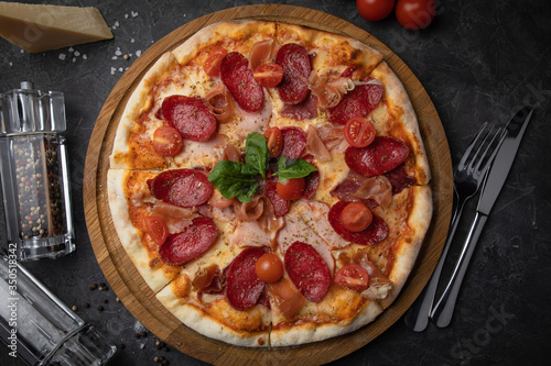  Italian pizza with tomatoes salami, parma, meat and cheese on a black background