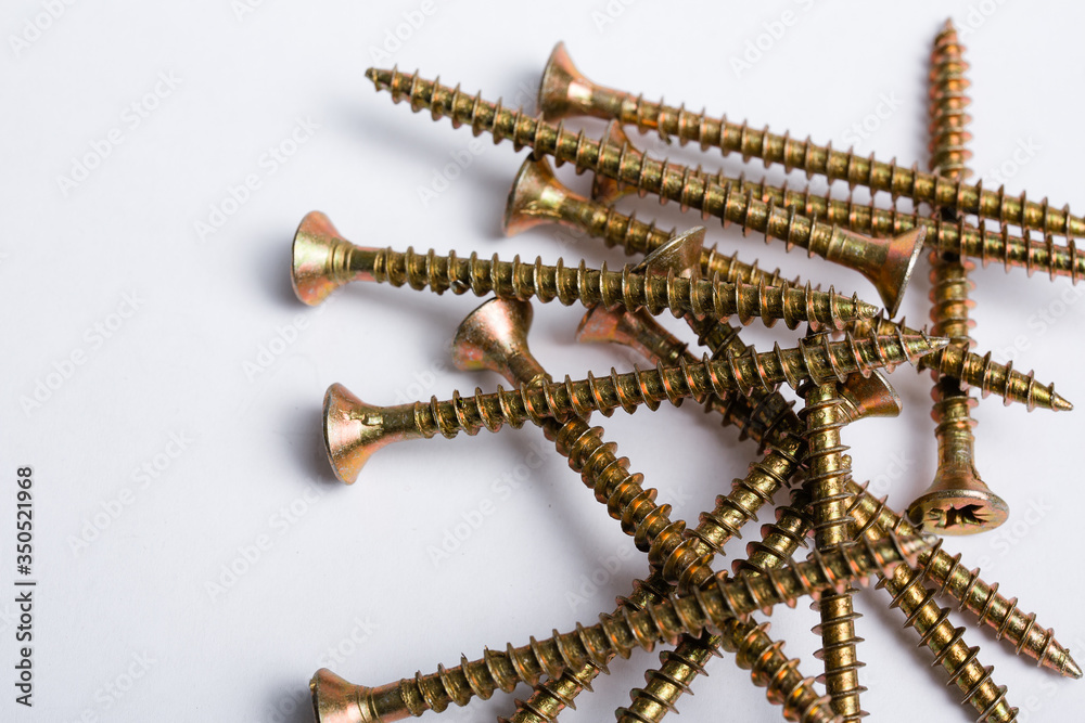 Yellow wood screws are randomly scattered on a white background. Zinc coating. Repair concept Yellow wood screws are randomly scattered on a white background. Zinc coating. Repair concept