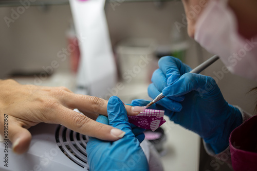 Personal care. Close up detail of professional hands rebuilding nails with special gel and tool. Professional manicure salon.