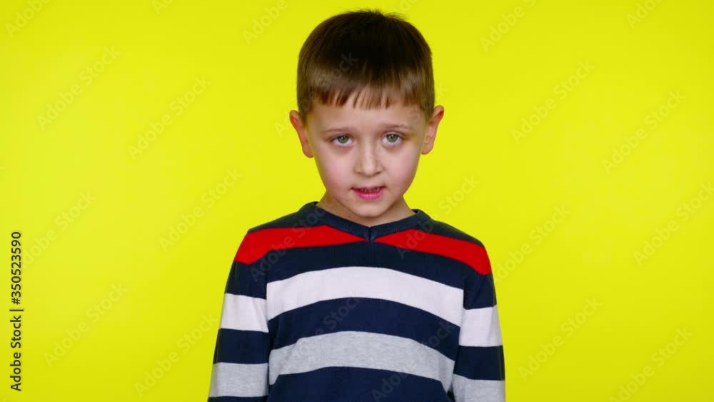 Serious little child boy in a colorful sweater says yes on a yellow background with copy space. Place for text or product. 4K slowmotion footage Serious little child boy in a colorful sweater says yes on a yellow background with copy space. Place for text or product. 4K slowmotion footage