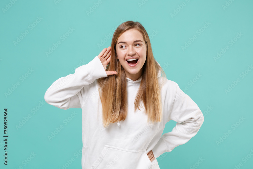 Cheerful young woman girl in casual white hoodie posing isolated on blue turquoise background studio portrait. People lifestyle concept. Mock up copy space. Try to hear you with hand gesture near ear. Cheerful young woman girl in casual white hoodie posing isolated on blue turquoise background studio portrait. People lifestyle concept. Mock up copy space. Try to hear you with hand gesture near ear.
