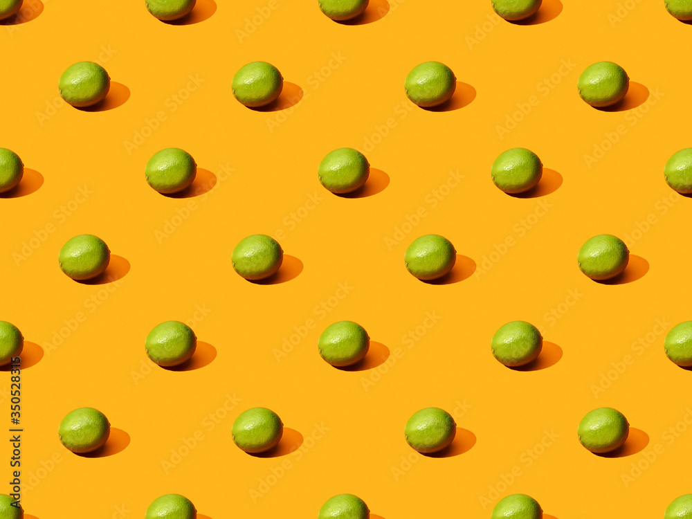 fresh whole limes on orange colorful background, seamless pattern