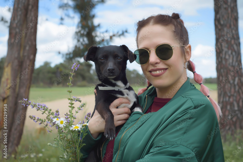 Woman in a green and flowery landscape with her dog in her arms. Idyllic place in spring. Woman in a green and flowery landscape with her dog in her arms. Idyllic place in spring.