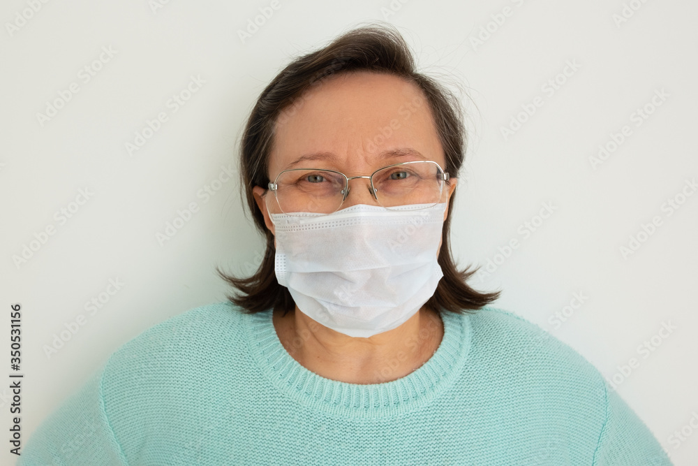 Mature woman wearing casual, glasses and medical face mask, posing isolated against white background. Closeup, front view. Epidemic or virus concept Mature woman wearing casual, glasses and medical face mask, posing isolated against white background. Closeup, front view. Epidemic or virus concept