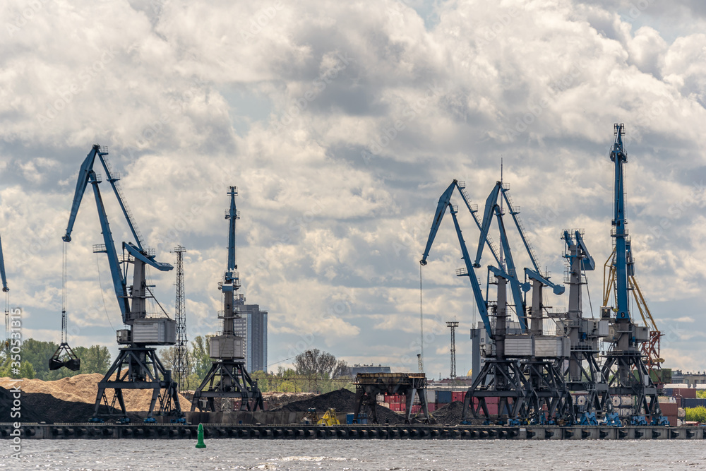 view from the river to the freight port with cranes and cargo containers.
