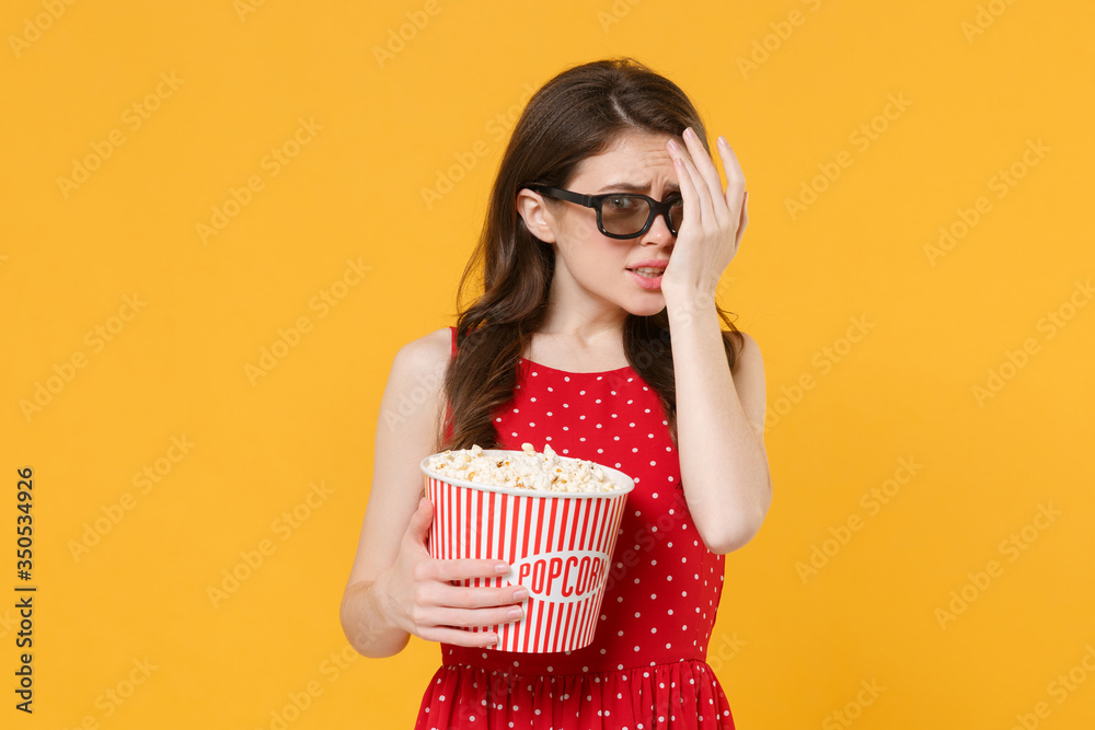 Scared woman girl in red summer dress, 3d glasses isolated on yellow background. People lifestyle concept. Mock up copy space. Watching movie film, hold bucket of popcorn, covering face with hand. Scared woman girl in red summer dress, 3d glasses isolated on yellow background. People lifestyle concept. Mock up copy space. Watching movie film, hold bucket of popcorn, covering face with hand.