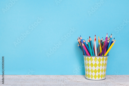 School colorful pencils in cup on blue background . Back to school and education concept.