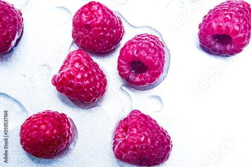 close-up of wet red raspberries on silver plate