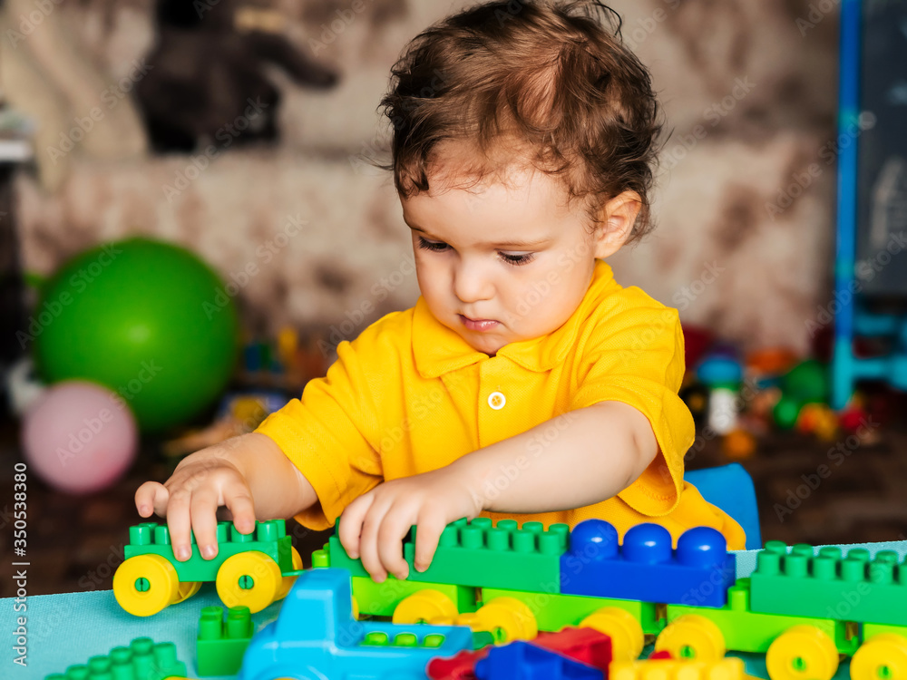 Obraz premium Child boy learns to build a house from blocks