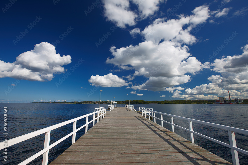 wooden pier in the sea against a blue cloudy sky