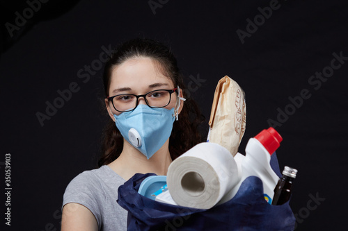 Young woman in a valve of the respiratory protective mask with a bag full of groceries from the supermarket. concept covidiots photo