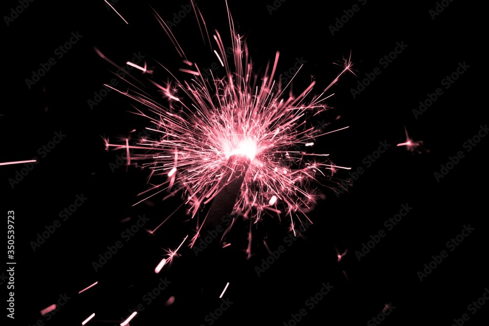 Red sparkler countdown on fire with spread of glitter sparks. Luxury entertainment at e.g. New Years Eve, Independence Day or birthday party celebration. Glowing light spark on dark background Red sparkler countdown on fire with spread of glitter sparks. Luxury entertainment at e.g. New Years Eve, Independence Day or birthday party celebration. Glowing light spark on dark background