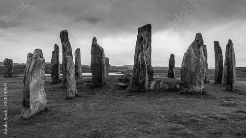 Ancient neolithic Callanish Stones are standing stones placed in a cruciform pattern with a central stone circle. Neolithic era, ritual focused in monochrome