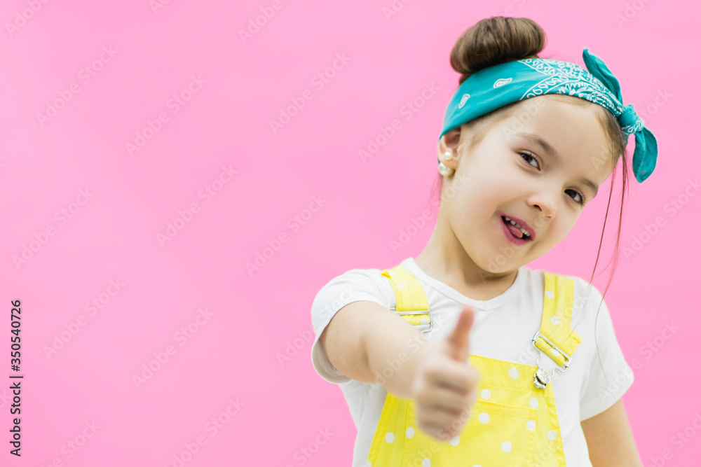 Shot where girl showing thumb up. Little girl looks suprised