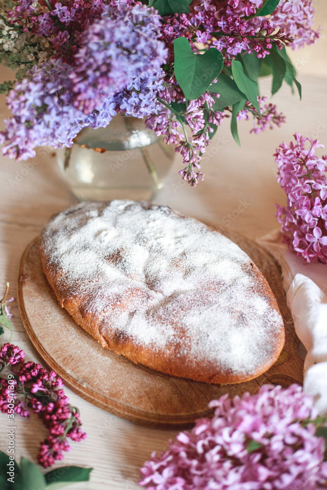 Homemade Apple pie on a wooden table next to a bowl of lilacs. Gentle toning. Homemade Apple pie on a wooden table next to a bowl of lilacs. Gentle toning.
