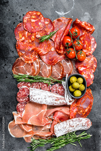 Spanish cold meat assortment. Chorizo, fuet, LOMO, jamon Iberico, olives. Black background. Top view.