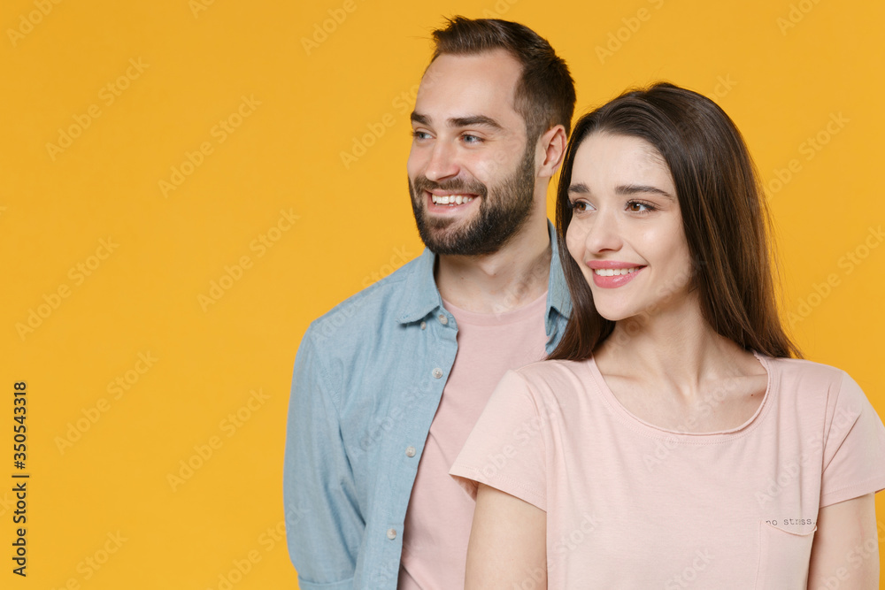 Smiling young couple two friends guy girl in pastel blue casual clothes posing isolated on yellow wall background studio portrait. People emotions lifestyle concept. Mock up copy space. Looking aside. Smiling young couple two friends guy girl in pastel blue casual clothes posing isolated on yellow wall background studio portrait. People emotions lifestyle concept. Mock up copy space. Looking aside.