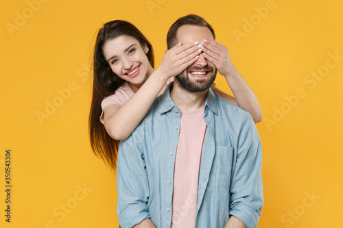 Smiling young couple two friends guy girl in pastel blue casual clothes posing isolated on yellow background studio portrait. People lifestyle concept. Mock up copy space. Covering eyes with hands.