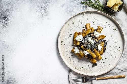Pasta tortiglioni with black truffle and Boletus edulis, white mushroom. Gray background. Top view. Space for text