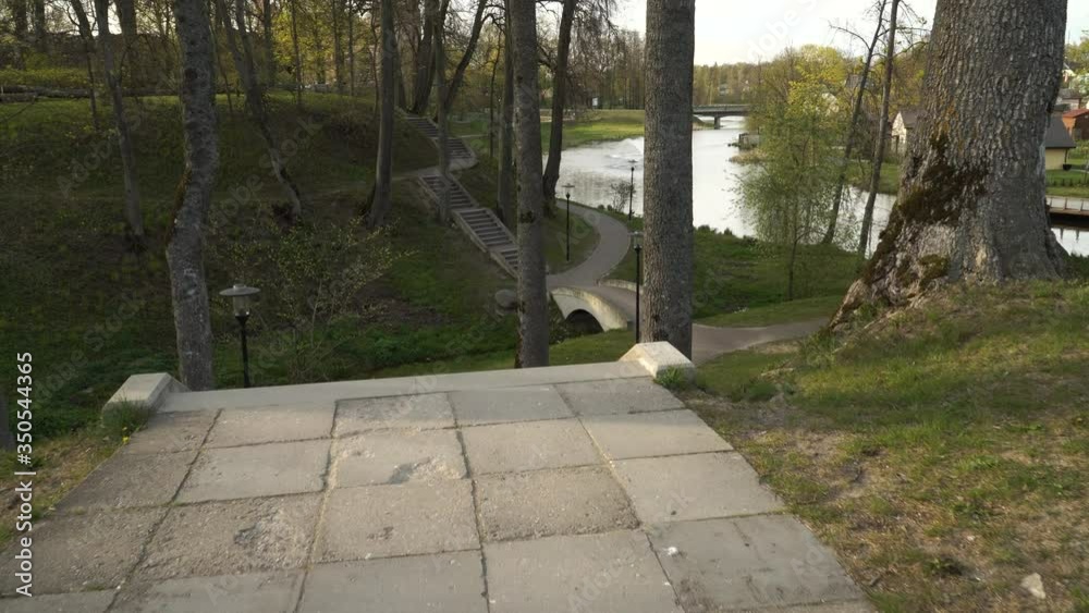 A cobblestone pathway with concrete stairs leading down and up to the hill. The castle mound in Dobele town, Latvia of 2020. The spring season panoramic landscape. A walk motion footage. A cobblestone pathway with concrete stairs leading down and up to the hill. The castle mound in Dobele town, Latvia of 2020. The spring season panoramic landscape. A walk motion footage.
