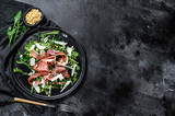 Salad with Parma, prosciutto ham, arugula and Parmesan. Black background, top view, space for text