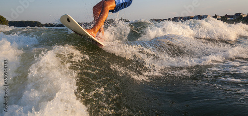 Man surfing on the Surfboard pulled by a motor boat over the boat wave Wakeboarder surfing fun leisure activity family outing water sports sporting health challenge
