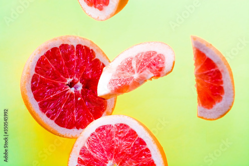 Bright, summer background with different slices of fresh and juicy grapefruit in the air.