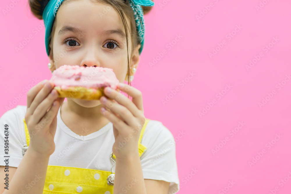 Little girl hiding behind a donut. Pink background