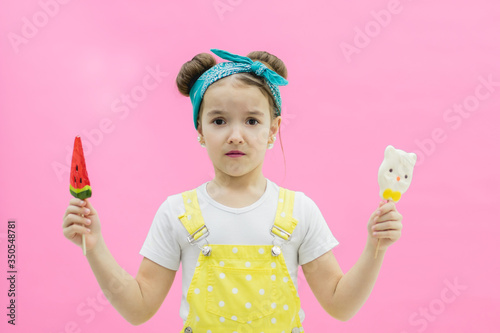 Fényképezés Little girl can not decide which one lollipop to choose.