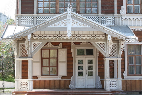 Porch door and ornamental windows with carved frames of Sukachyov's old wooden house in Irkutsk city (Russia). Museum-estate of V. P. Sukachev. Russian folk style in architecture. Landmark of Irkutsk photo