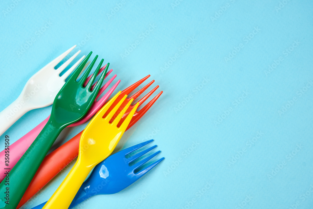 Multicolored plastic dishes on a blue background. The concept of environmental pollution by plastic, ecolog place for text, flat lay Multicolored plastic dishes on a blue background. The concept of environmental pollution by plastic, ecolog place for text, flat lay